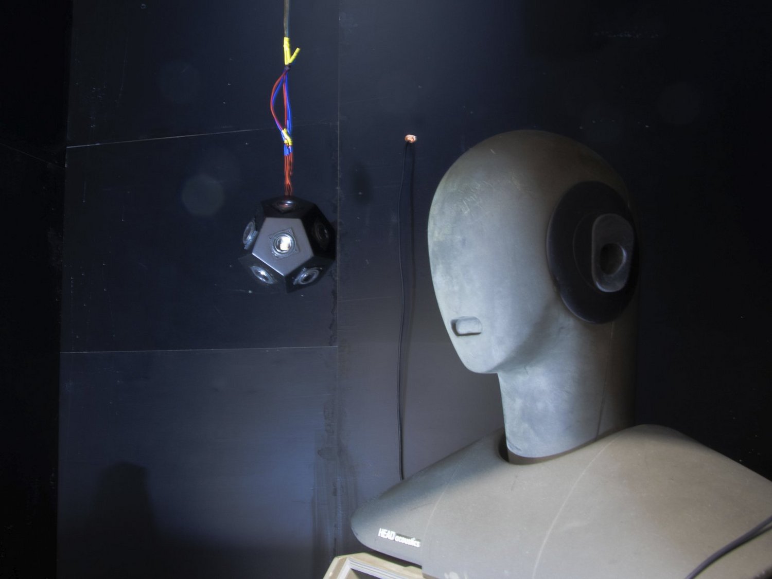 Akustik-Messkopf und abgehängtem Dodekaeder-Lautsprecher in schwarzer schalltoter Kammer