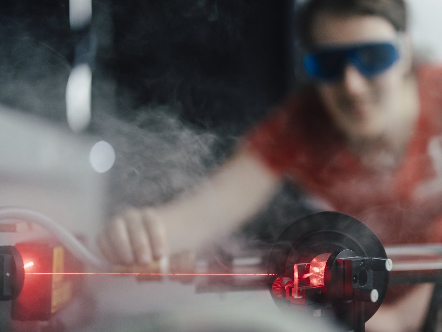 Eine Person mit Schutzbrille betrachtet Laserstrahlen.