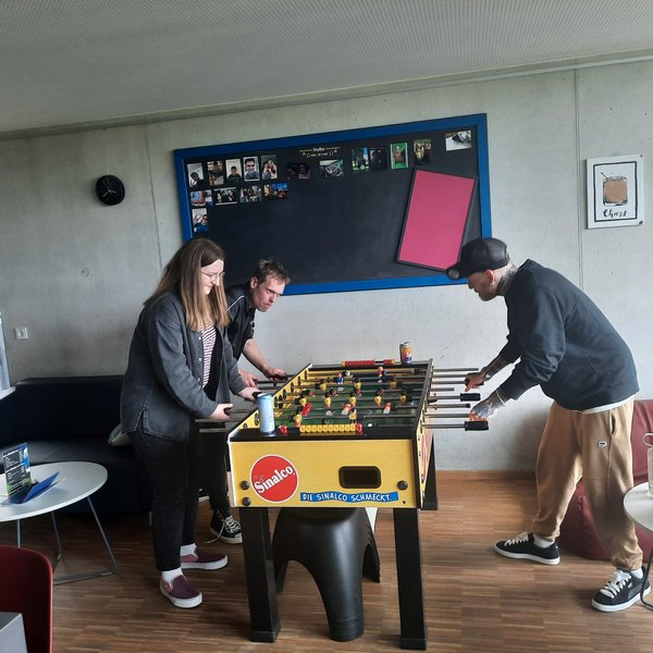 Studierende Spielen Kicker in einer Einrichtung der Kinder- und Jugendhilfe.
